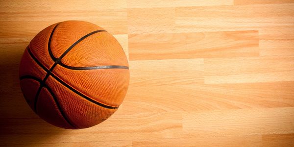 A basketball on a wooden court floor.