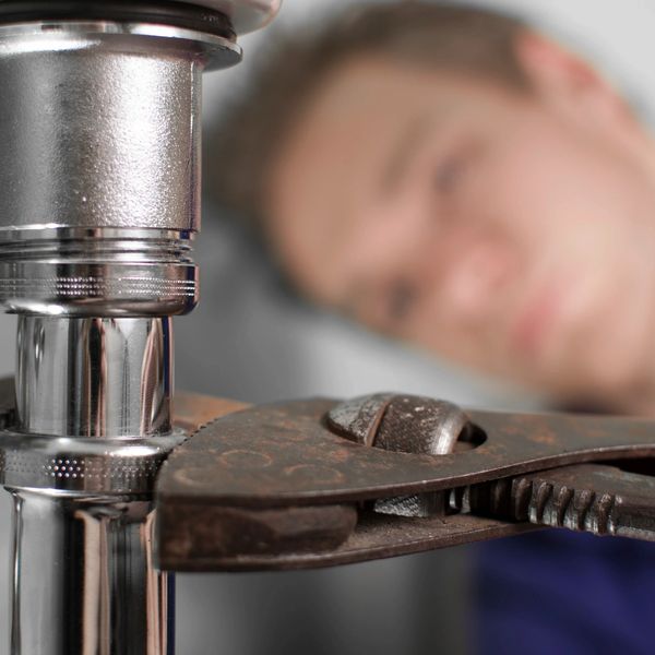A person tightening a pipe with a wrench.