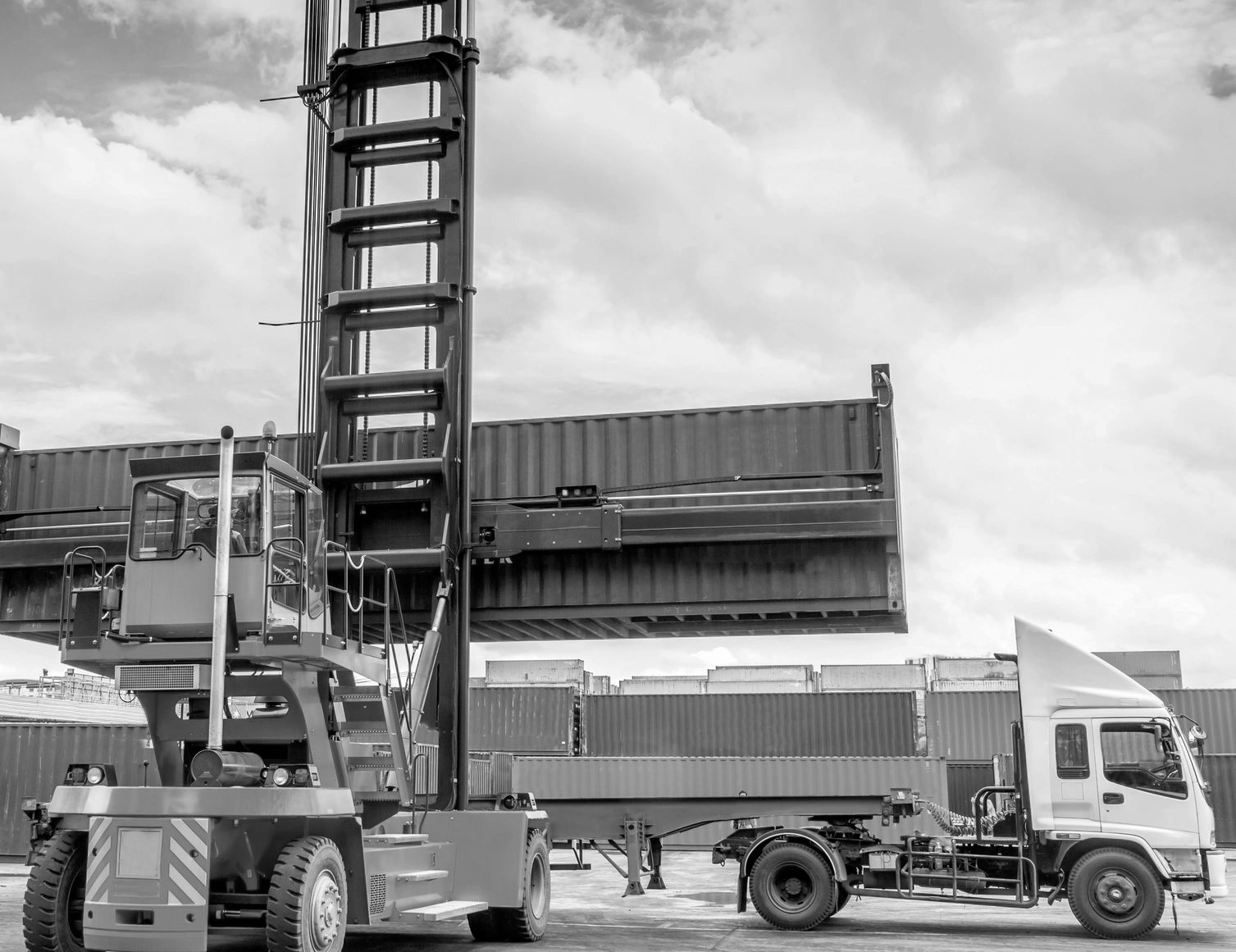 Motor forklift being used to lift cargo container onto truck flatbed.