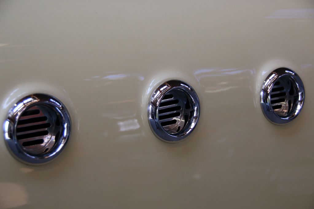 Close-up of three circular air vents on a beige surface.