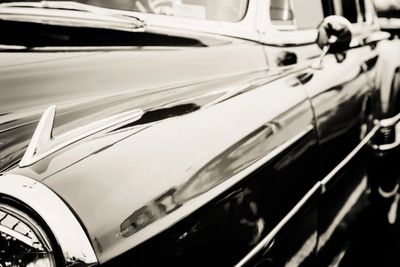 Close-up of a shiny vintage car's side in black and white.