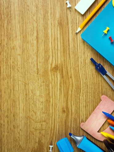 Wooden desk with scattered school supplies.