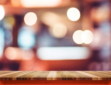 Wooden table with blurred lights background.