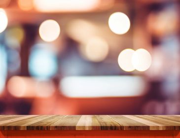 Wooden table with blurred lights background.