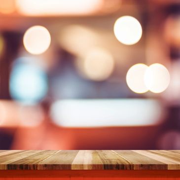 Empty wooden table with blurred lights in background.