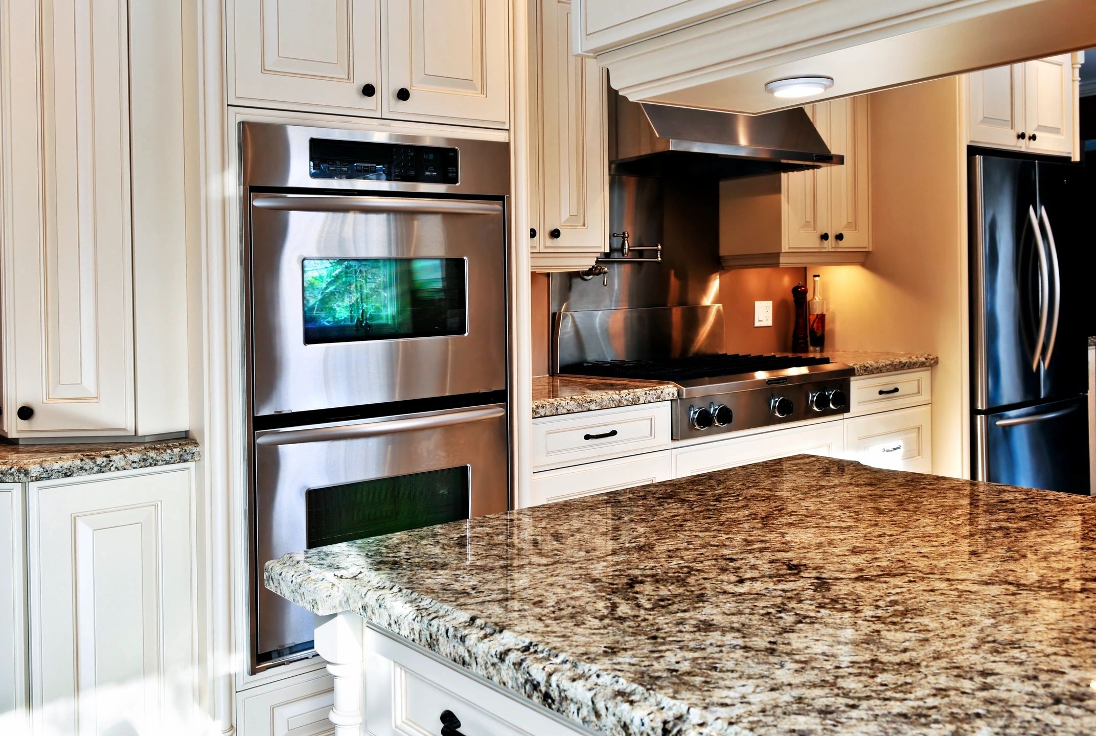 Kitchen with white cabinets, and stainless-steel wall oven,  cooktop and French door fridge