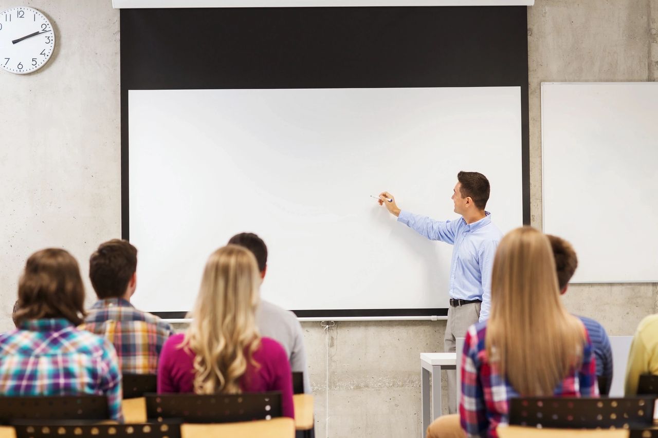 students in a classroom watching a teach teach a lesson