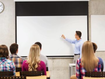 Teacher explaining lesson on whiteboard to attentive students.