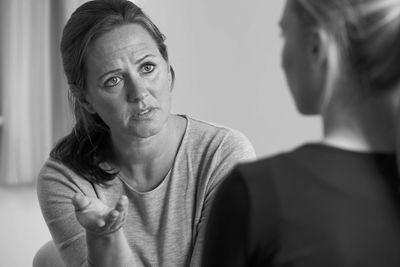 A woman speaking seriously to another person in a black and white photo.
