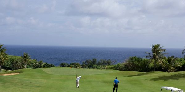 two people playing golf on a fairway and green at a golf course with a golf buggy