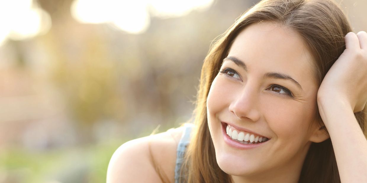 Young woman smiling outdoors with a bright and happy expression.