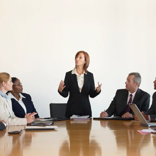 A woman leading a business meeting with attentive colleagues around a conference table.