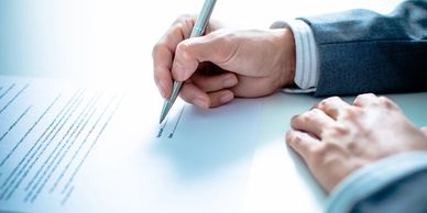 A person signing a document with a pen.