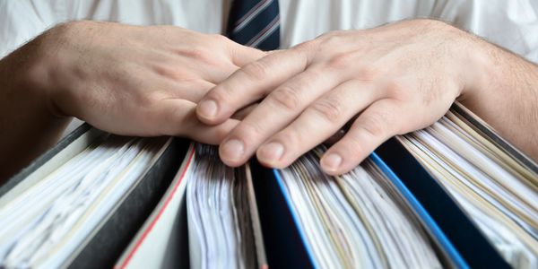 A bookkeeper pulling several book files to create financial reports.