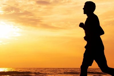 Man running on beach as sun rises