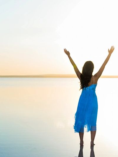 Woman on shore with raised arms