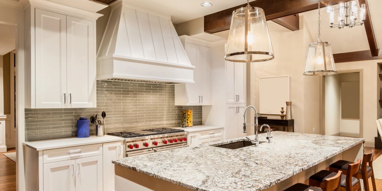 Modern kitchen with granite island and pendant lights.