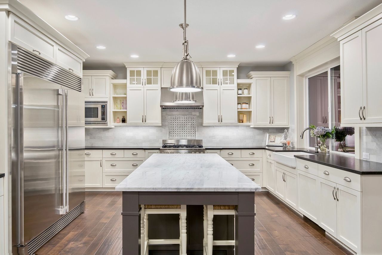 A newly remodeled kitchen with white cabinets, black countertops and stainless steel appliances.