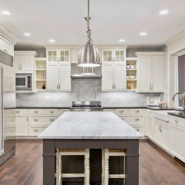 Modern white kitchen with island and stainless steel appliances.