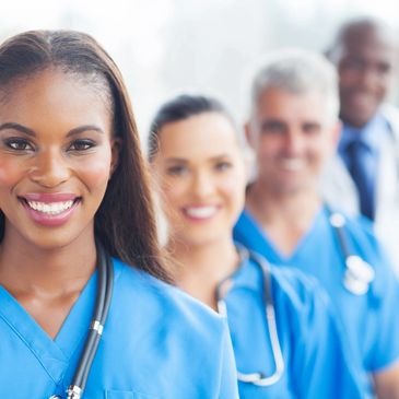 A group of Healthcare Professionals standing and smiling with stethoscopes around their necks.
