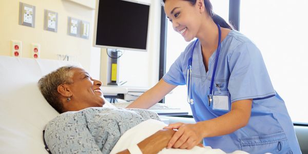 Nurse smiling and leaning forward to talk to smiling patient