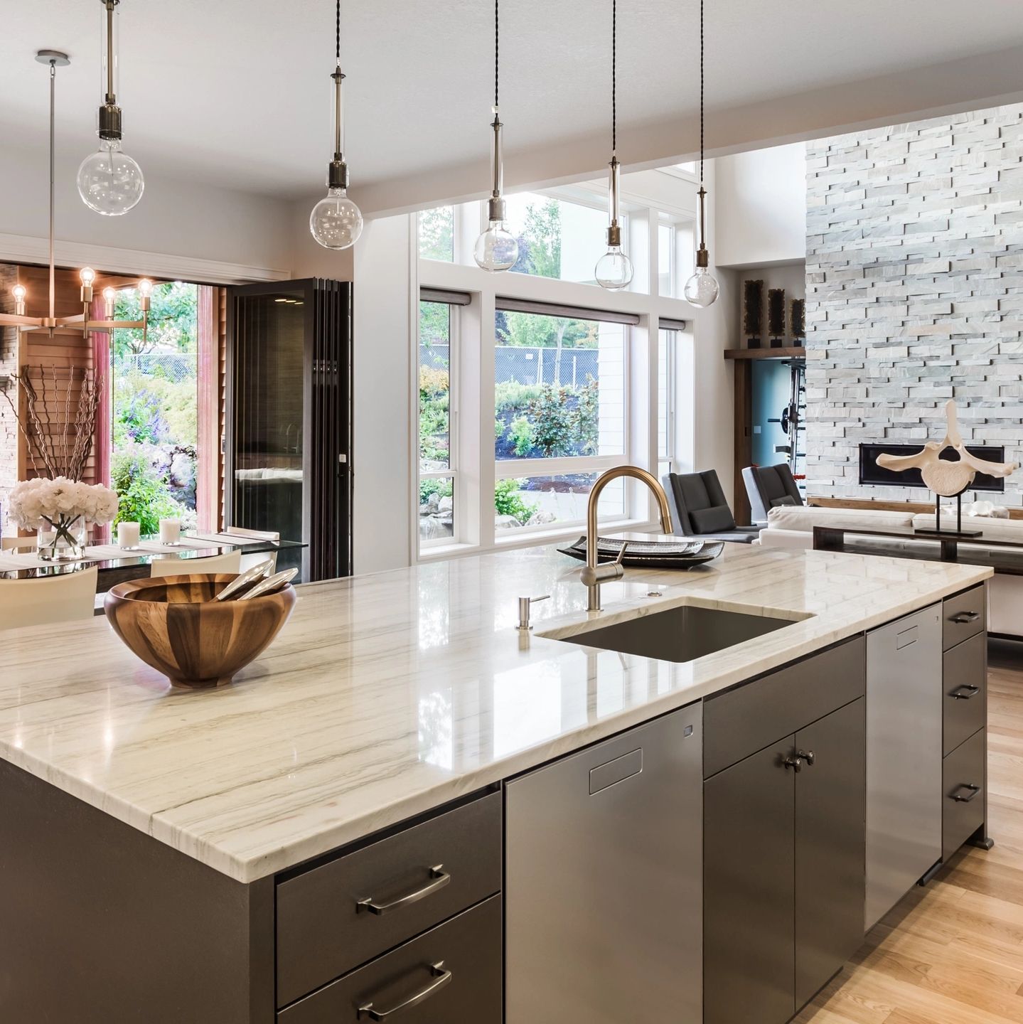 Modern kitchen with marble island and pendant lights.