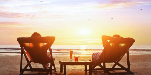 Couple Relaxing on the beach enjoying cocktails while watching the setting sun