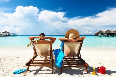 A couple is relaxing on the beach in beach chairs overlooking the ocean.