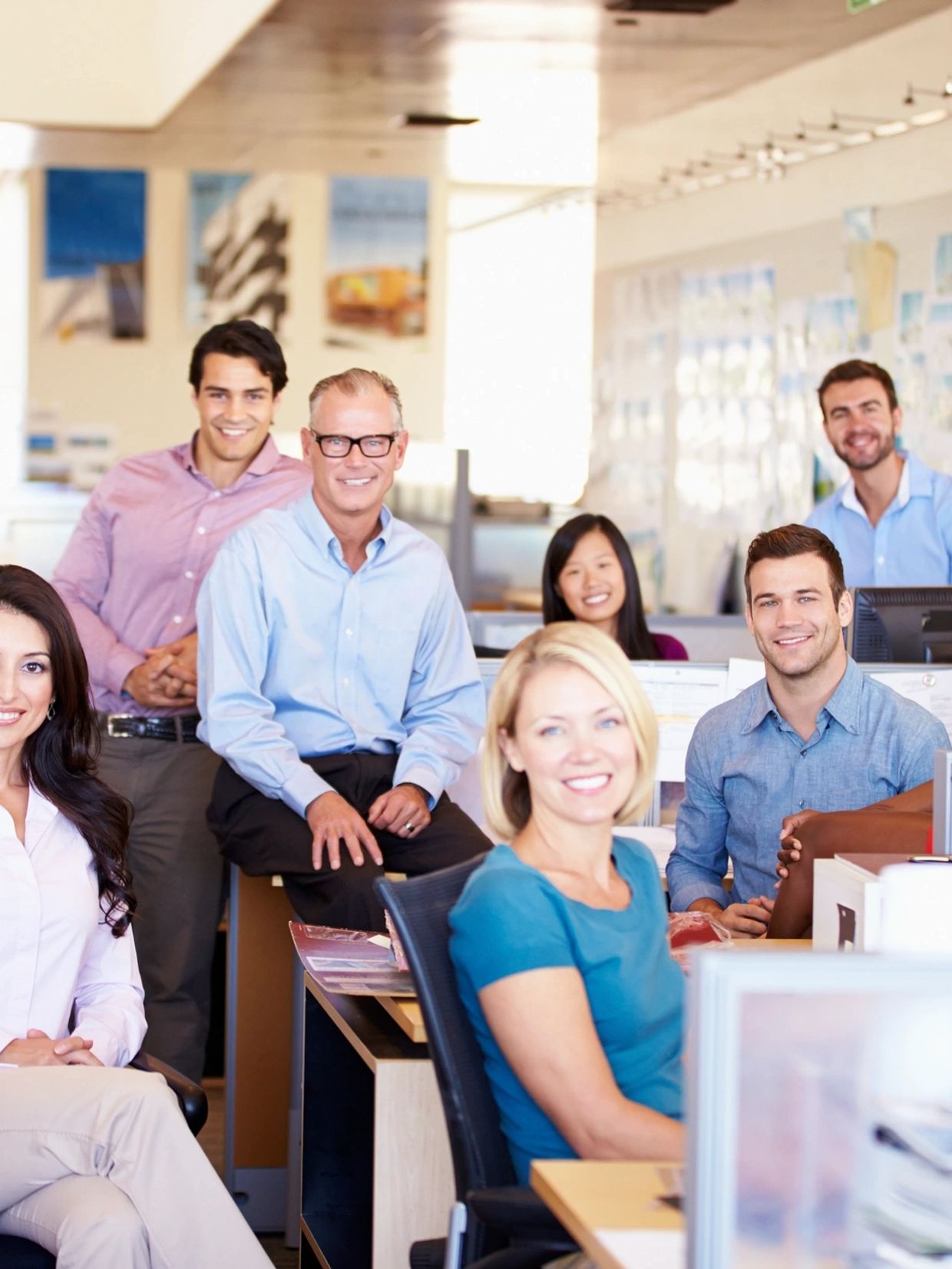 A diverse group of professionals smiling in a modern office workspace.