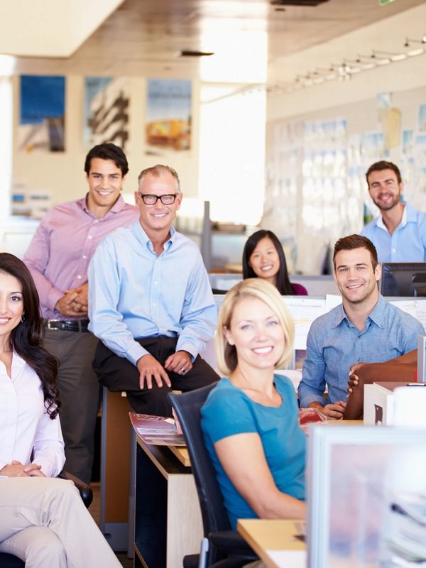 A diverse group of professionals smiling in a modern office workspace.