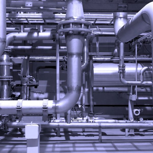 Industrial metal pipes and valves in a factory setting.