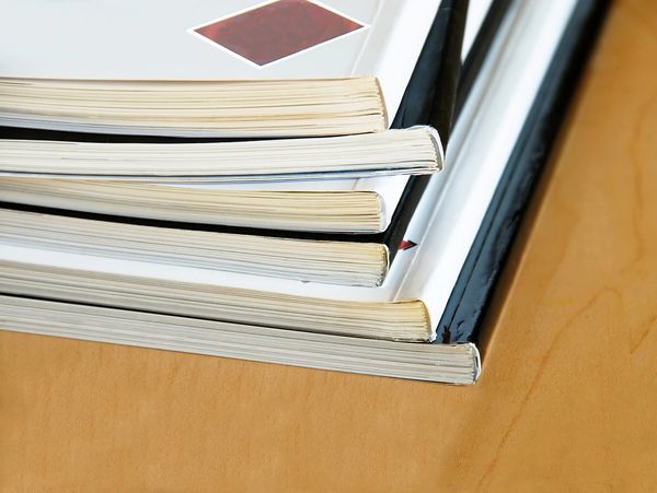Stack of books or magazines neatly arranged on a wooden surface.