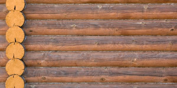 Wooden log wall with horizontal logs and vertical log ends.