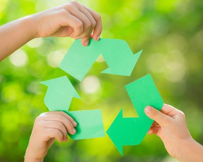 Three hands holding curved arrows to create the classic recycling symbol