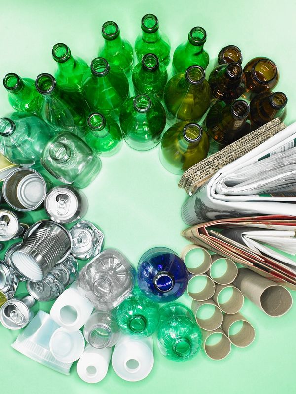 Recyclable materials arranged in a circle on a green background.