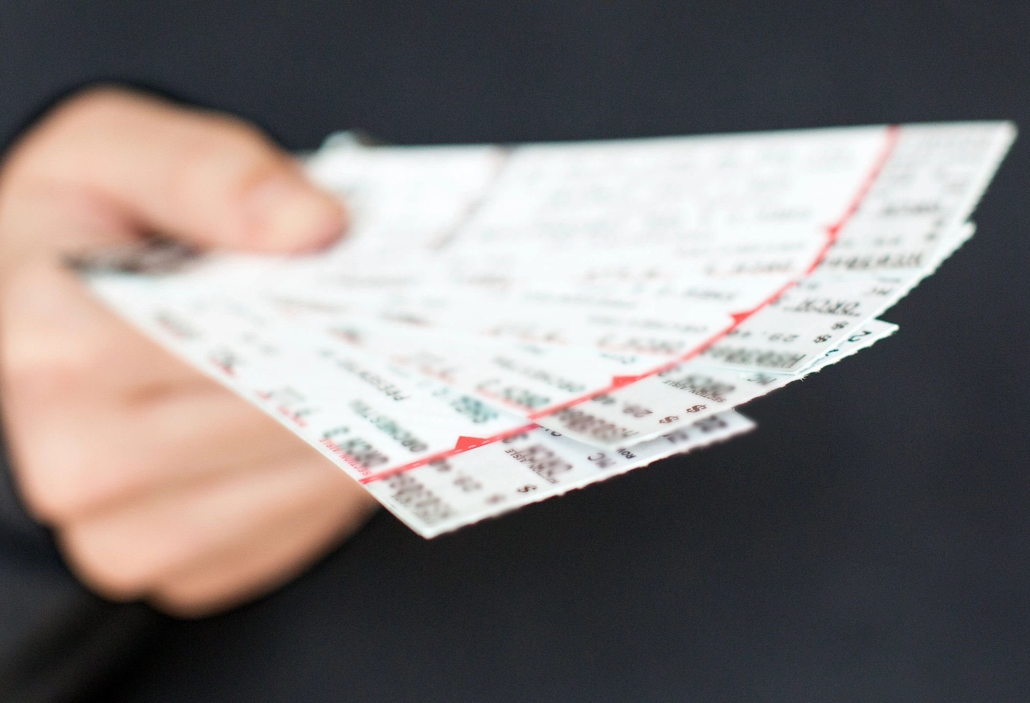 Hand holding a fan of lottery tickets with numbers and red markings.