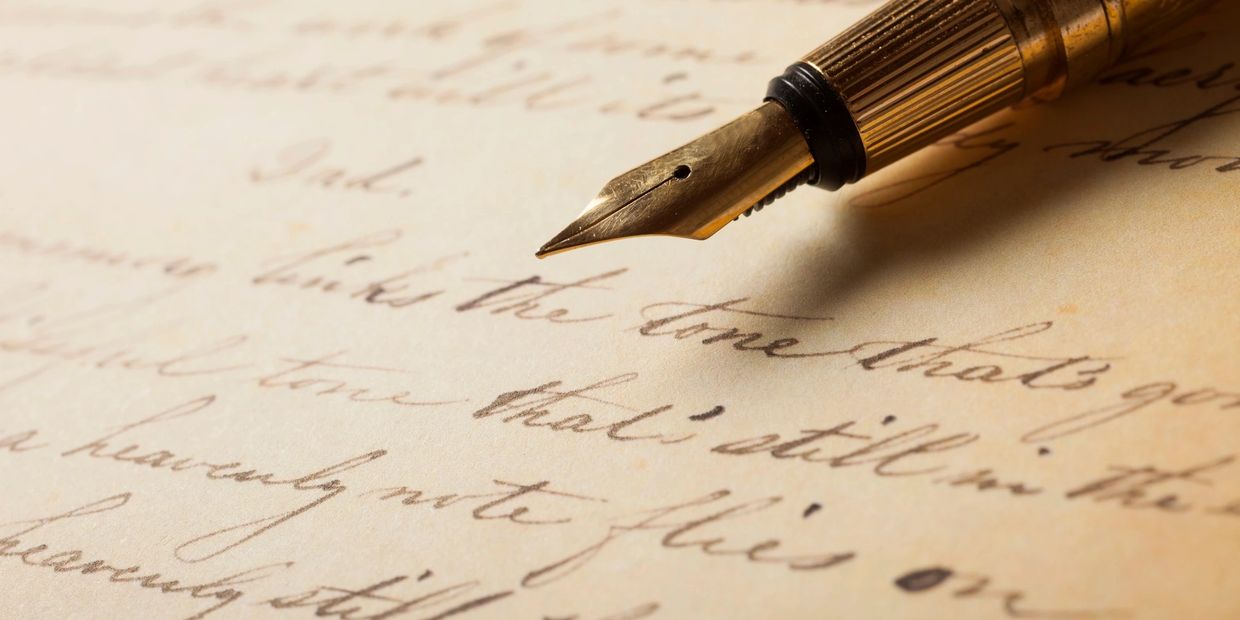 Close-up of a vintage fountain pen writing on aged paper.