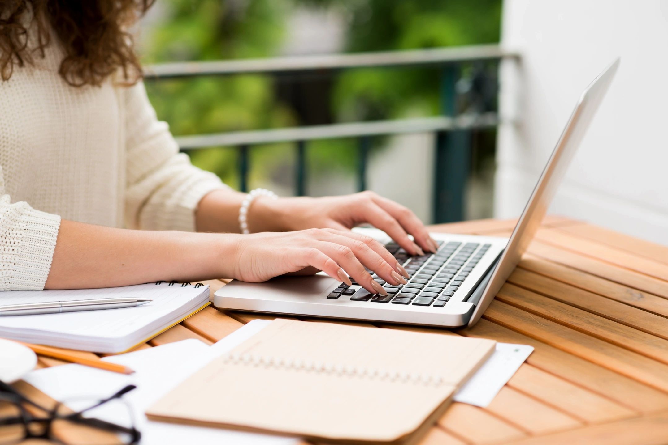 Woman sitting at desk typing on laptop keyboard.