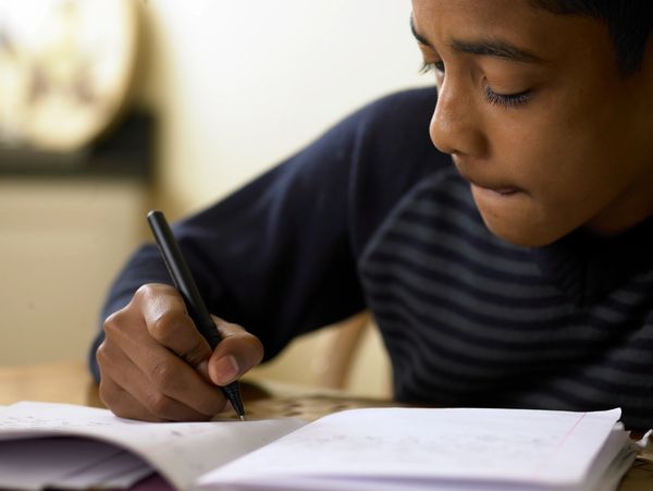 boy holding pen writing in notebook