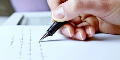 A woman writing with an ink pen on the paper 