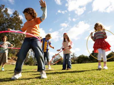 Children playing with hula hoops outside on a sunny day.