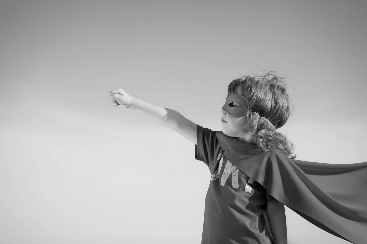 A young superhero putting his fist in the air. 