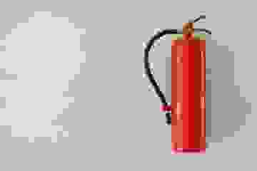 A red fire extinguisher hanging on a wall