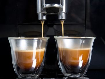 Two shots of espresso being brewed into glass cups from a coffee machine.