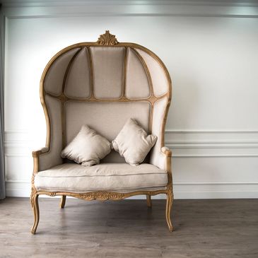 Elegant vintage canopy armchair with beige upholstery and wooden frame.