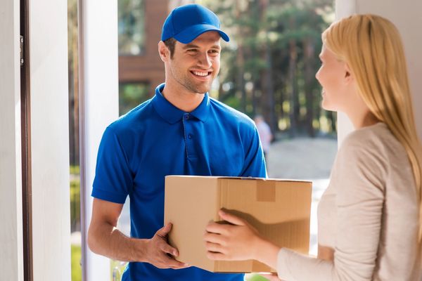 delivery driver handing a box to a lady on her door step 