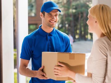 Delivery person handing a package to a woman at her door.