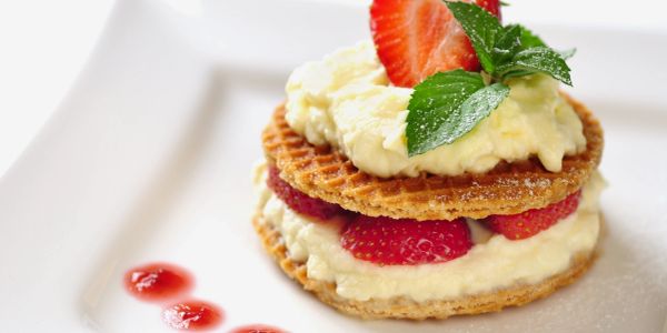 Dessert with wafers, cream, strawberries, and mint.