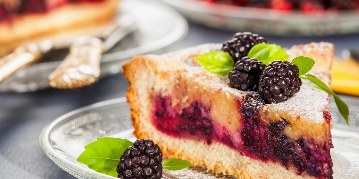 Slice of blackberry pie with fresh blackberries and mint.