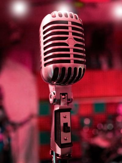 Close-up of a vintage microphone with a pink and red background.